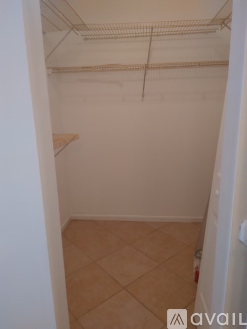 Empty white closet with tan tile floor.