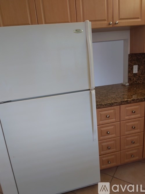 A white fridge in a kitchen with brown drawers.