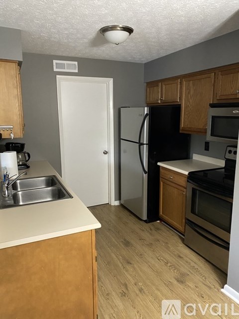 A kitchen with wooden cabinets and a black fridge.