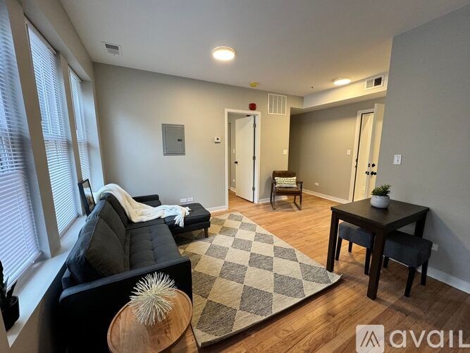 A living room with a black couch, a wooden table, and a rug.