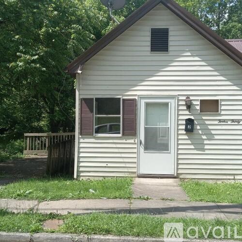 A small white house with a brown roof and a white door.