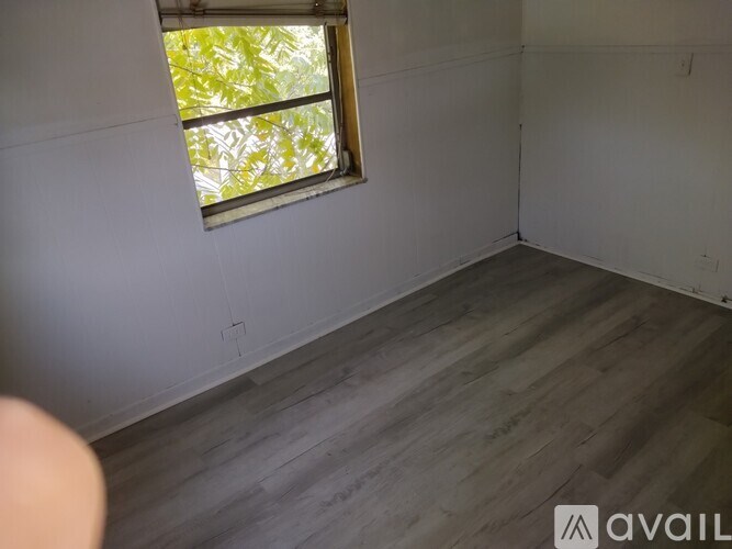 A room with a window and wooden flooring.
