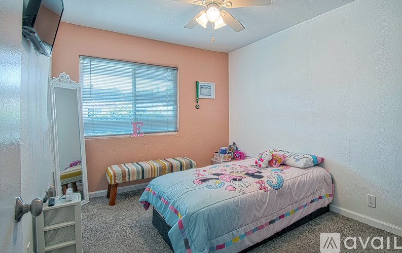 A bedroom with a bed, a window, and a ceiling fan.