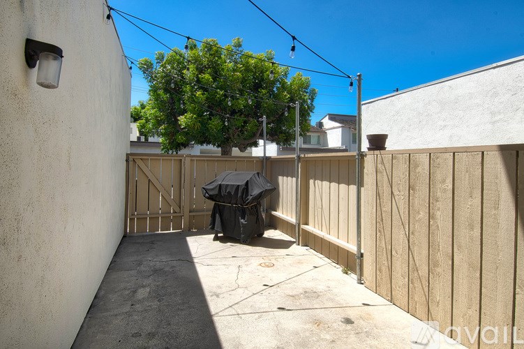 A patio with a black umbrella and a wooden fence.