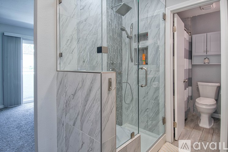 A bathroom with a walk-in shower and a toilet in the corner.