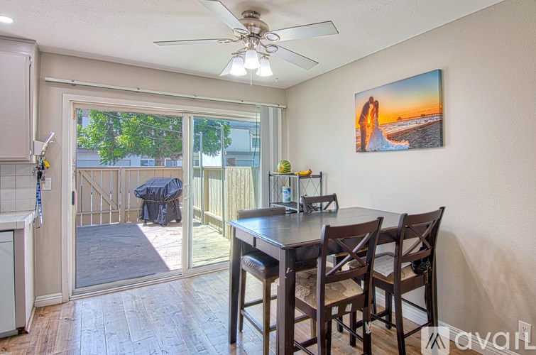 A dining room with a table and chairs and a painting of a beach scene on the wall.