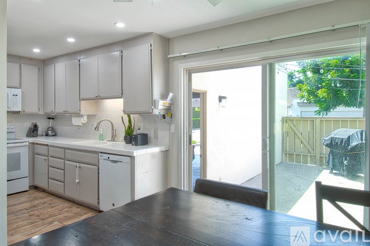 A kitchen with white cabinets and a wooden floor.