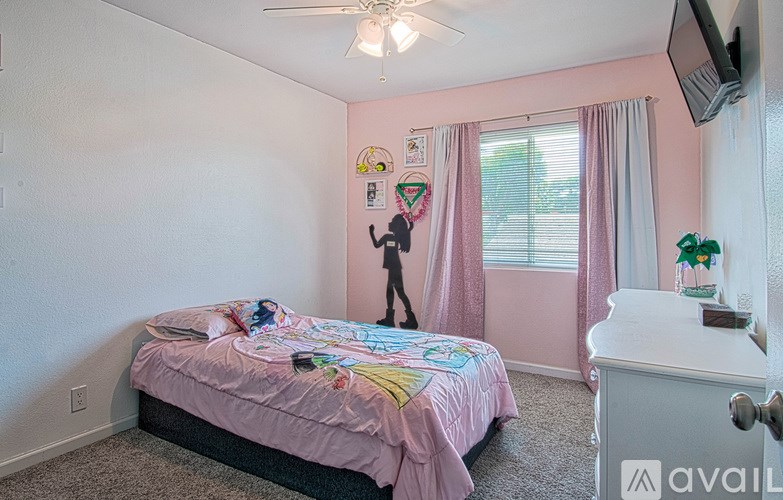 A bedroom with a bed, dresser, and window with pink curtains.
