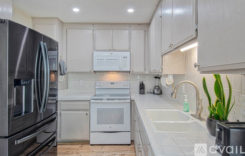 A kitchen with white cabinets and a stainless steel refrigerator.