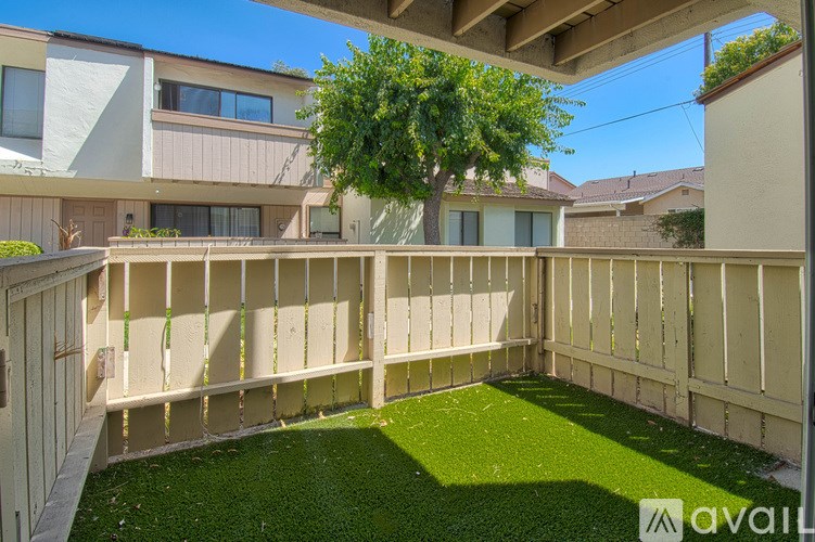 A backyard with a wooden fence and a green lawn.