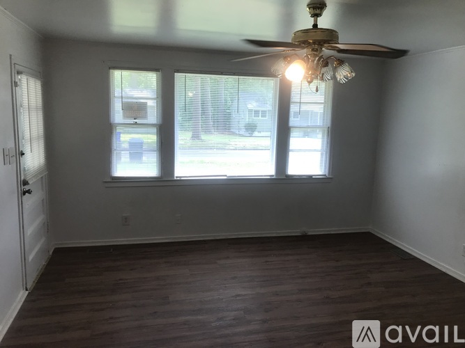 A room with a ceiling fan and two windows.