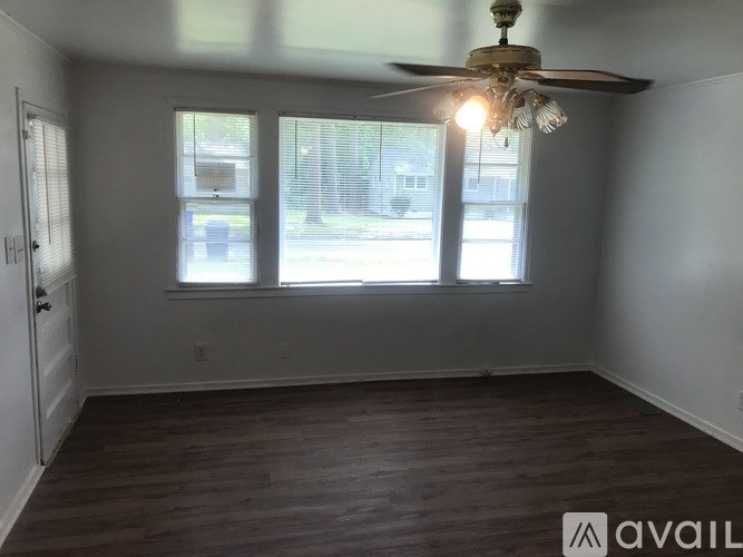 A room with a ceiling fan and two windows.