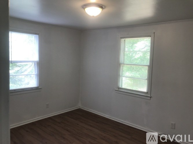 A room with two windows and wooden floors is available.
