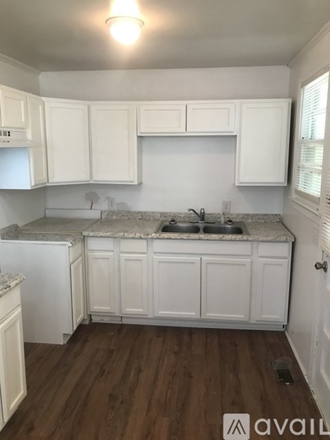 A kitchen with white cabinets and a granite countertop.