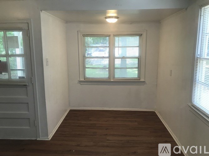 A room with a wooden floor and a window with blinds.