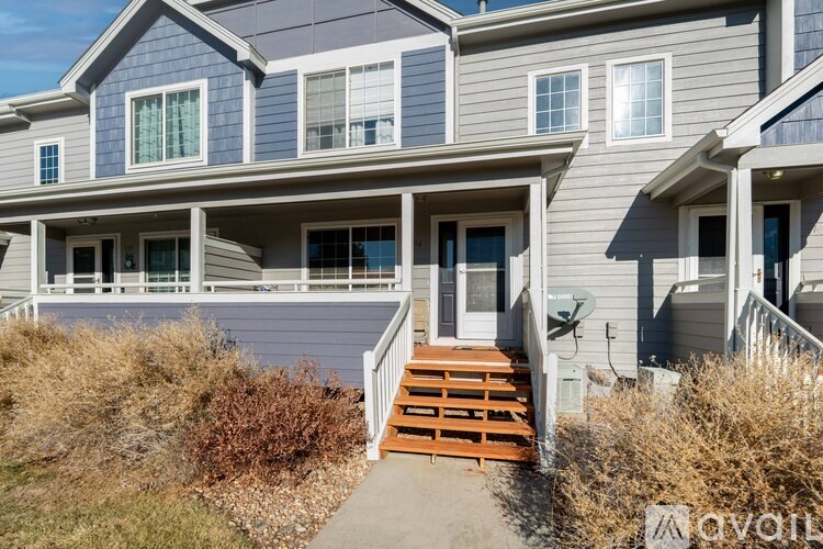A two-story house with a wooden staircase leading to the front door.