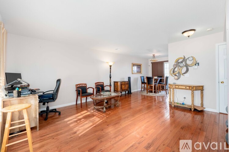 A room with wooden floors and furniture including a desk and chairs.