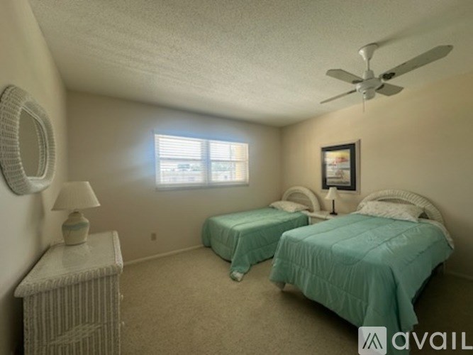 A bedroom with two beds and a fan.