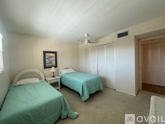 A bedroom with two beds and a ceiling fan.