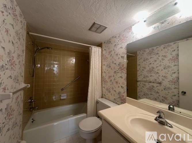 A bathroom with floral wallpaper and a white bathtub.