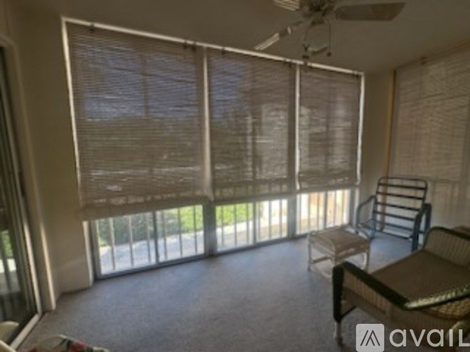 A room with a fan, a table and chairs, and a window with blinds.