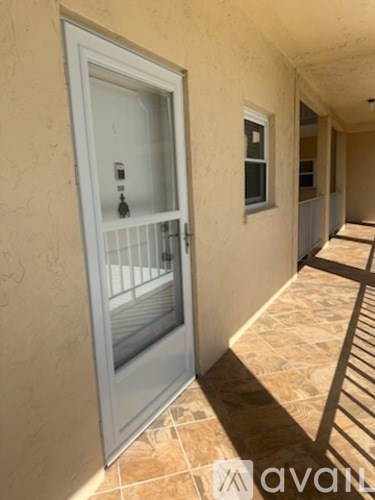 A white door with a glass window is on the left side of a hallway with tiled floors.