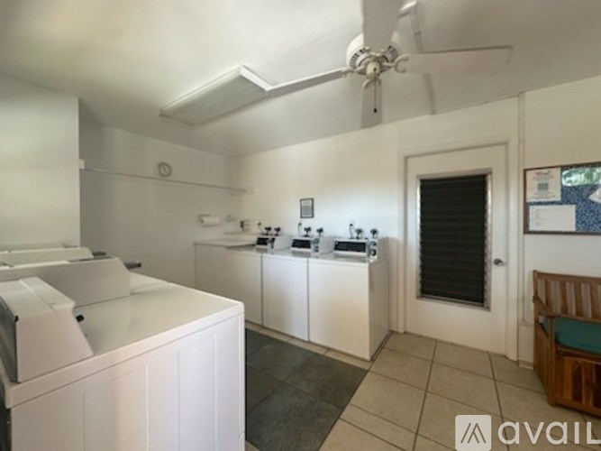 A laundry room with a washer and dryer, a fan, and a cabinet.