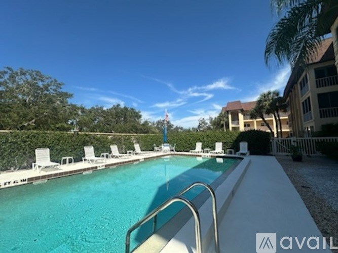A swimming pool with a metal ladder and white chairs.