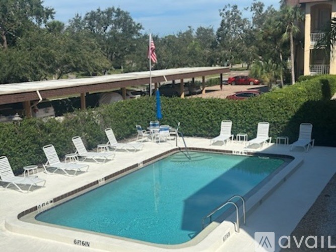 A pool with chairs around it and a flag on a pole.