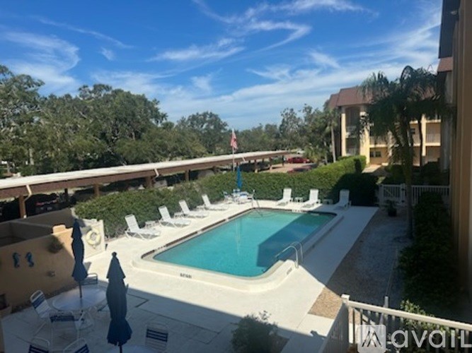 A pool surrounded by chairs and trees.