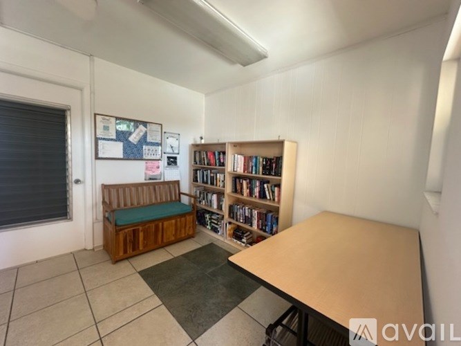 A room with a bench, a table, and a bookshelf filled with books.