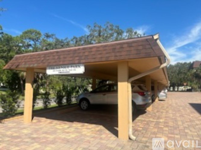 A carport with a sign that reads "CARPORT" is situated on a brick driveway.