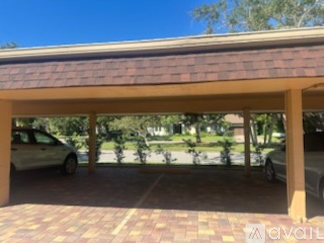 A carport with a brick floor and a tiled roof.