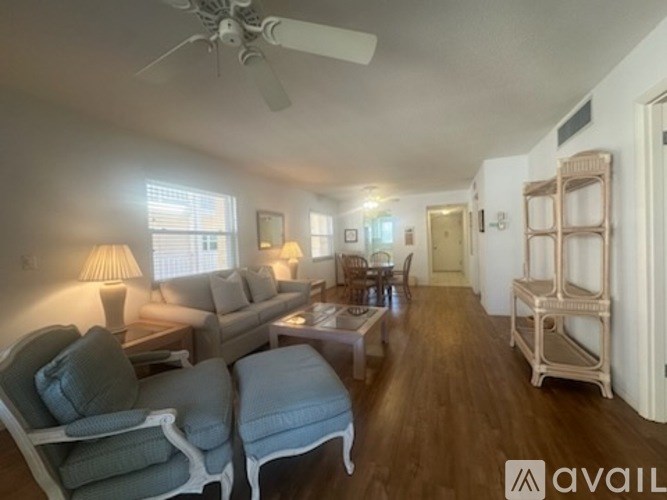 A living room with a couch, chairs, and a fan.