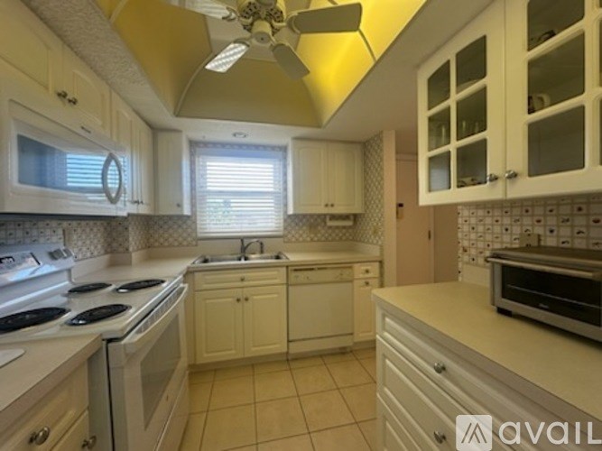 A kitchen with white cabinets and a tile floor.
