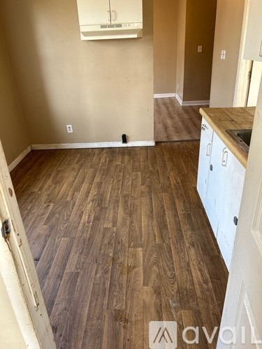 A room with wooden flooring and a white cabinet.