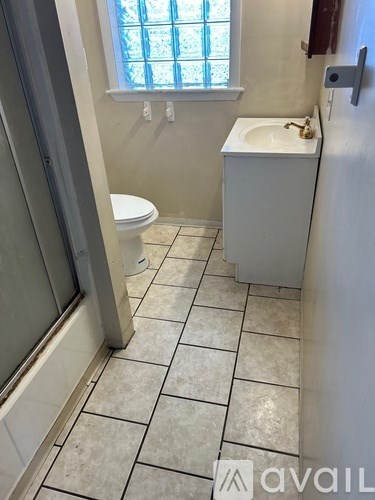 A bathroom with a toilet, sink, and tiled floor.