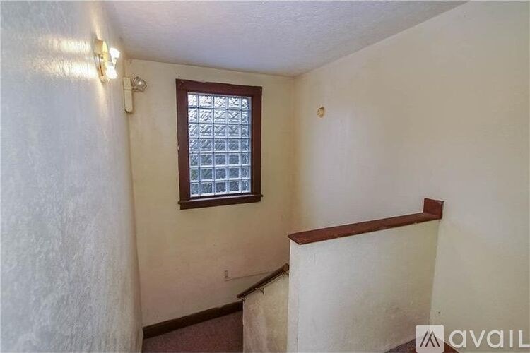 A small room with a window and a light switch on the wall.