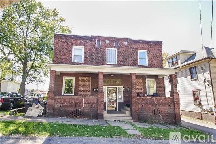 A two-story brick house with a front porch and a garage door.