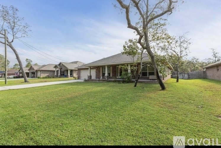 A grassy area in front of a house with a tree in the foreground.