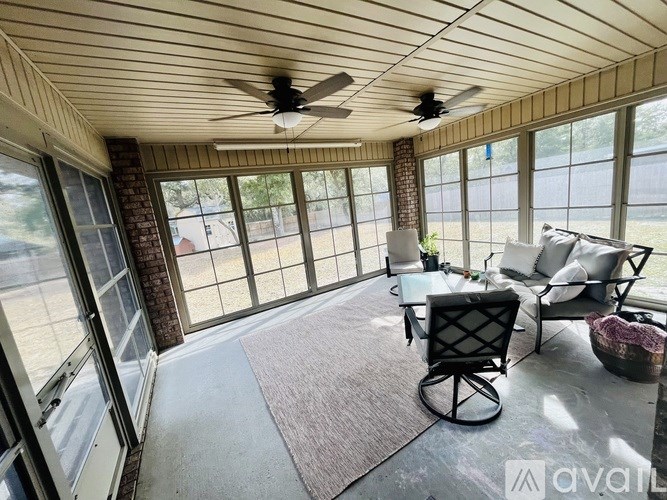 A sunroom with a ceiling fan and a table with chairs.