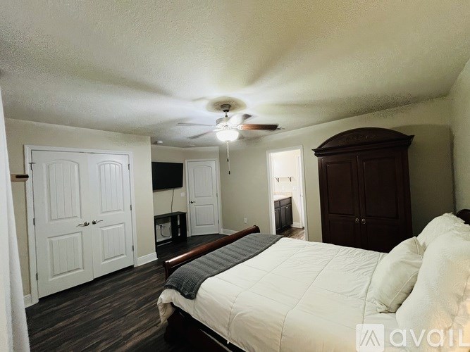 A bedroom with a bed, dresser, and ceiling fan.