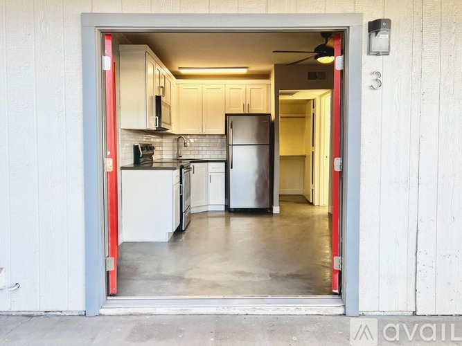 A kitchen with a refrigerator, microwave, and oven is visible through a doorway.