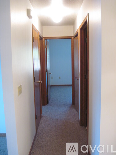 A hallway with carpeted floors and white walls.