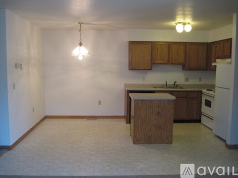 A kitchen with a white wall and wooden cabinets.