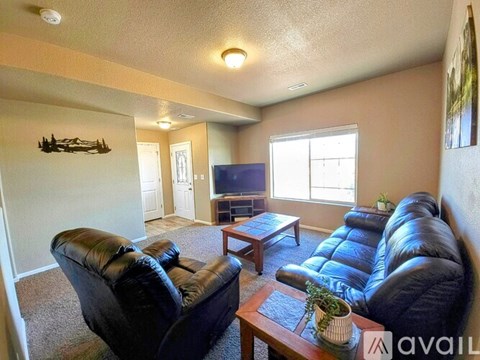A living room with black leather furniture and a flat screen TV.