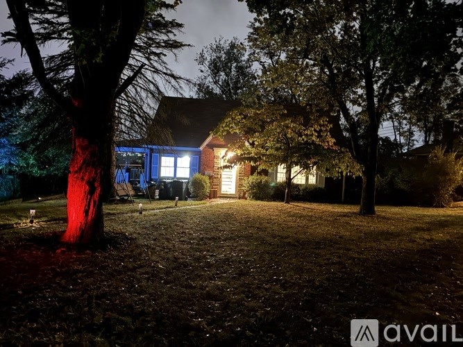 A house is lit up at night with a tree in front of it.