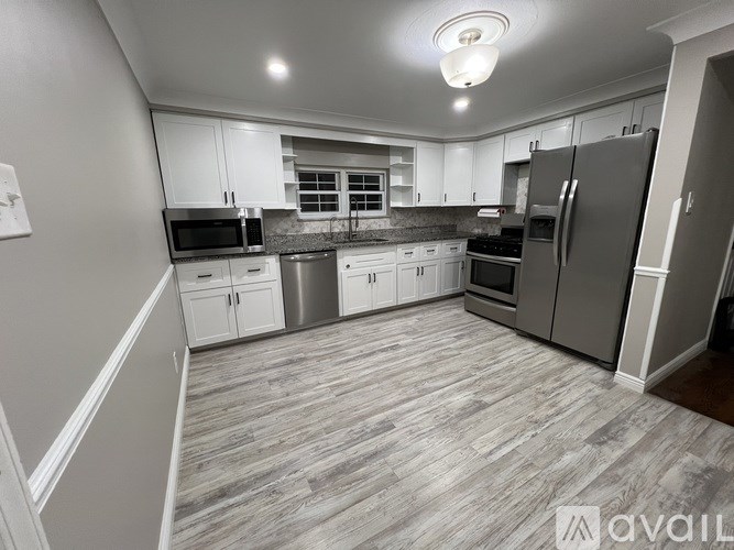 A kitchen with white cabinets and a wooden floor.