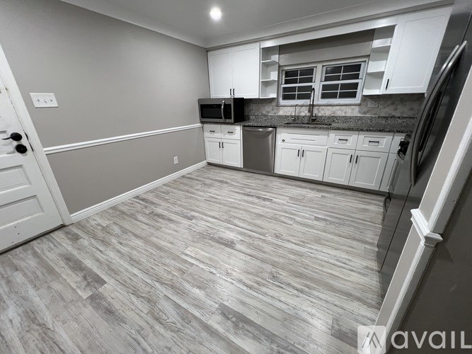 A kitchen with a grey floor and white cabinets.