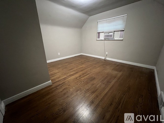 A room with wooden flooring and a window with blinds.